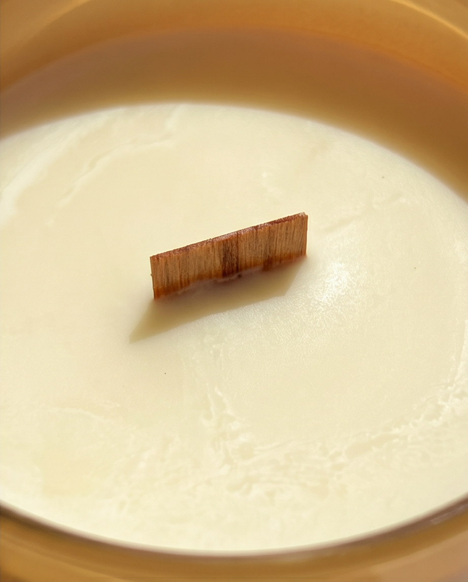 Close-up overhead view into the Hope crystal-infused soy candle by The Phoenix Candles, showing an FSC-certified wooden wick centered in a smooth ivory soy wax surface with subtle natural wax texture visible, framed by the warm matte canary yellow glass vessel rim.