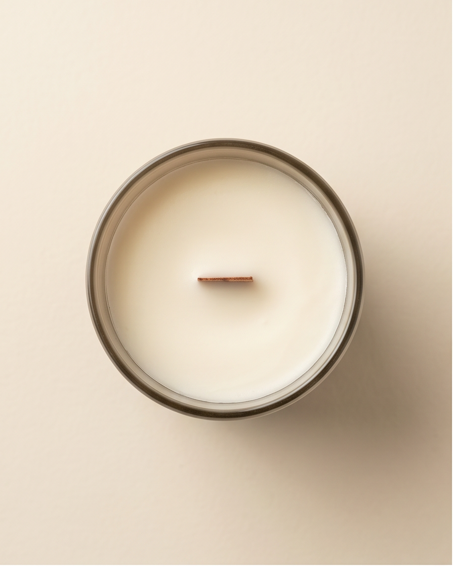 Directly overhead view of the Intuition crystal-infused soy candle by The Phoenix Candles, looking down into the open matte stonewashed grey vessel revealing a perfectly smooth ivory soy wax pour with an FSC-certified wooden wick centered precisely in the frame, on a warm cream background.